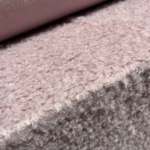 Pu&ograve; includere: Primo piano di un tessuto morbido, soffice e rosa chiaro con una texture pelosa.