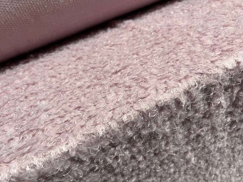 Pu&ograve; includere: Primo piano di un tessuto morbido, soffice e rosa chiaro con una texture pelosa.