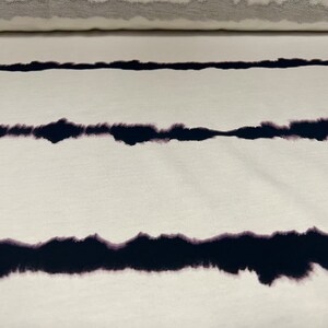 May include: White fabric with black tie-dye stripes. The stripes are a faded, uneven, and slightly blurred black.