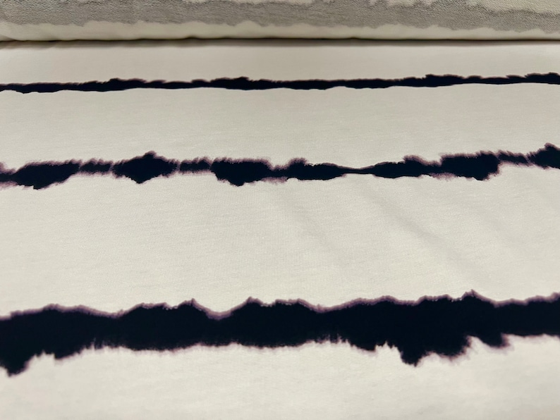 May include: White fabric with black tie-dye stripes. The stripes are a faded, uneven, and slightly blurred black.