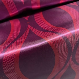 May include: Purple satin fabric with a red patterned design of wavy lines and dots.
