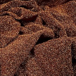 以下が含まれることがあります： テクスチャのある表面を持つ、茶色のキラキラした布のクローズアップ。