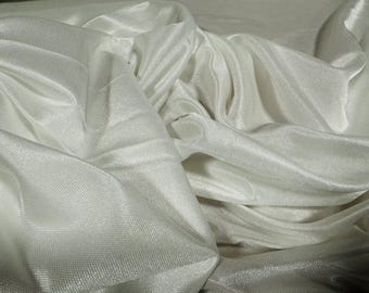 May include: White silky fabric with a smooth, flowing texture. The fabric is draped and folded, creating soft, rounded shapes.