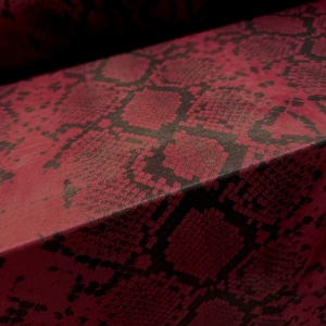 Könnte beinhalten: Nahaufnahme eines burgunderfarbenen Stoffes mit einem schwarzen Schlangenhautmuster.