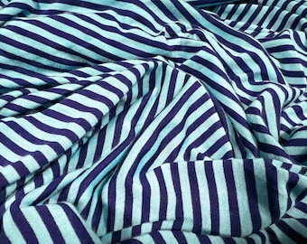 May include: Close-up of a blue and navy striped fabric. The fabric is wrinkled and folded, showing the texture of the material.