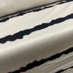 May include: White fabric with black horizontal stripes. The stripes are a tie-dye pattern, giving them a slightly blurred look.