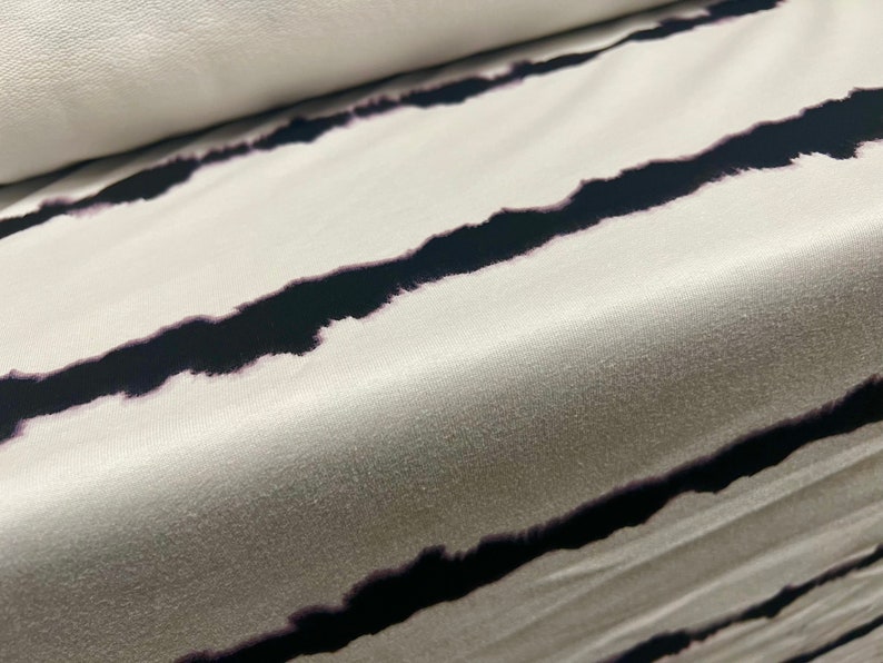 May include: White fabric with black horizontal stripes. The stripes are a tie-dye pattern, giving them a slightly blurred look.