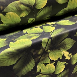 May include: Black fabric with a green leaf pattern. The leaves are a light green with a yellow tint and are arranged in a random pattern.
