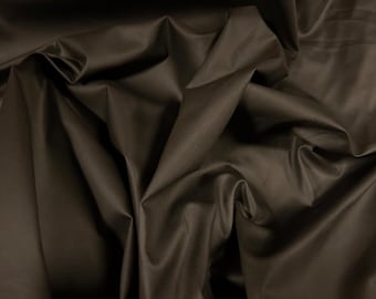 May include: A close-up of a dark brown fabric with a smooth, silky texture. The fabric is draped and folded, creating soft, flowing lines.