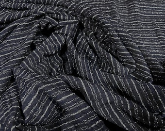 May include: Close-up of a black fabric with silver stripes. The fabric is wrinkled and has a shimmery texture.