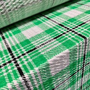 Puede incluir: Tela de cuadros verde y blanca con rayas negras. La tela tiene una superficie texturizada.