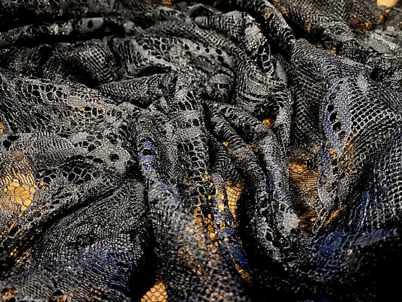 May include: Black lace fabric with a delicate floral pattern. The fabric is soft and flowing, with a slightly textured surface.