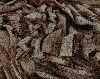 May include: Close-up of a brown and white striped fabric with a textured, fuzzy surface.