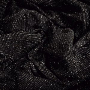 May include: Close-up of a black fabric with a ribbed texture and a subtle sparkle. The material is draped, creating folds and shadows that enhance the visual depth. The fabric's surface is dotted with tiny, reflective specks.
