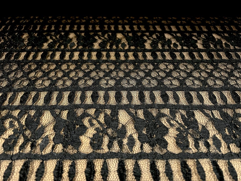 Pu&ograve; includere: Tessuto di pizzo nero con un motivo geometrico. Il pizzo &egrave; delicato e intricato, con una variet&agrave; di forme e dimensioni diverse.