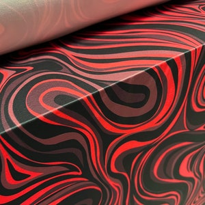 May include: Red, black and grey abstract swirl pattern fabric. The fabric has a smooth, silky texture.