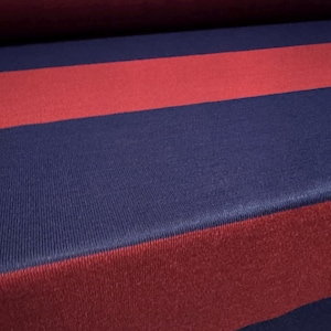 Peut inclure: Tissu rayé avec des rayures rouges et bleu marine alternées. Le tissu a un aspect texturé et tricoté.