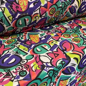 May include: White fabric with a colorful, abstract print featuring geometric shapes, swirls, and the words "Hot Mess" and "Switch".