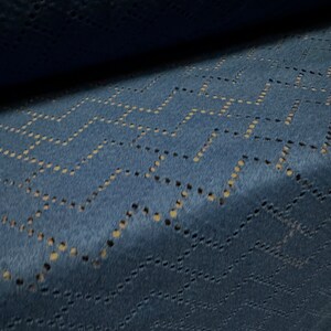 May include: Close-up of a blue fabric with a geometric pattern of small holes. The fabric has a soft, fuzzy texture.