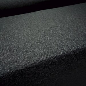 May include: Close-up of a black textured fabric. The fabric has a subtle, pebbled texture.