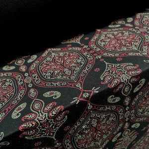 May include: Black fabric with a paisley pattern in shades of red, cream, and black.