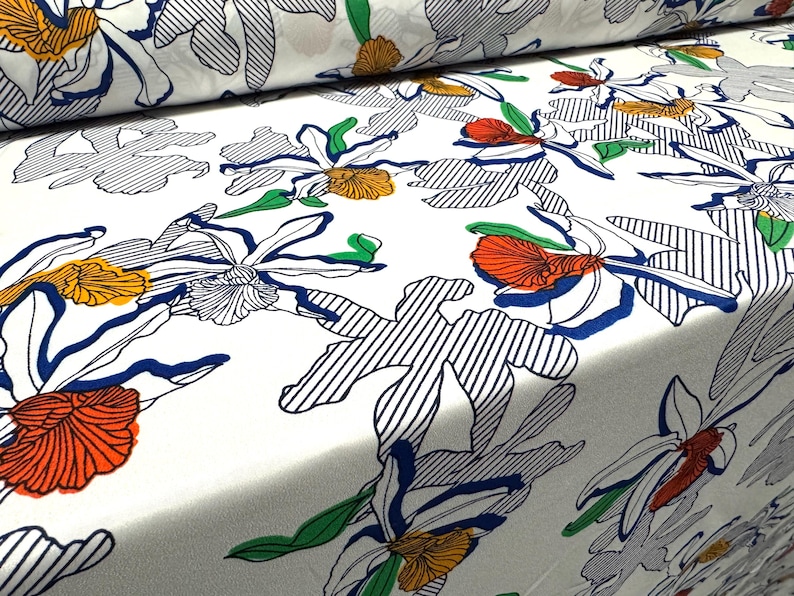 May include: White fabric with a floral pattern. The flowers are outlined in black and blue, with orange and red accents. The background is white with thin blue stripes.