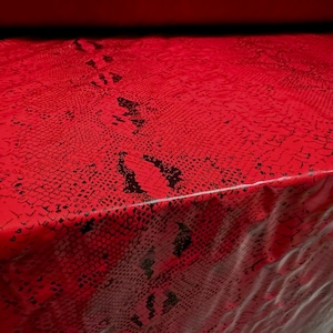 May include: Red fabric with a black snake skin pattern.