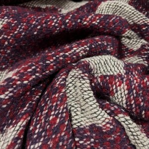 May include: Close-up of a woven fabric with a plaid pattern in shades of burgundy, white, and gray.