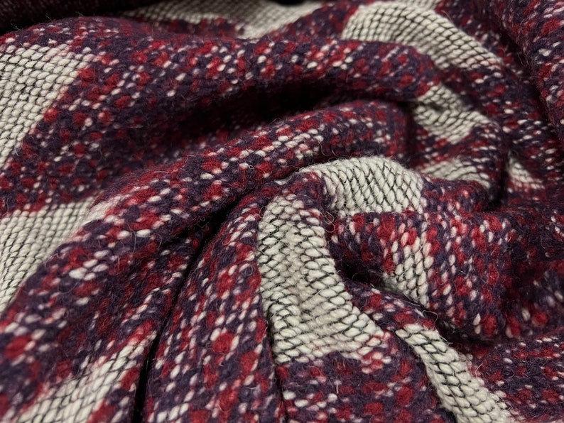 May include: Close-up of a woven fabric with a plaid pattern in shades of burgundy, white, and gray.