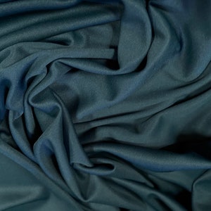 May include: A close-up of a dark blue fabric with a smooth, silky texture. The fabric is draped and folded, creating soft, flowing lines.