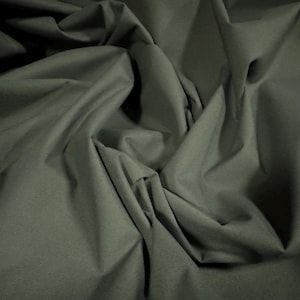 May include: A close-up of a dark green fabric with a smooth texture. The fabric is folded and draped, creating soft folds and curves.