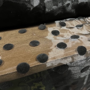 May include: Black sheer fabric with large black velvet polka dots. The fabric is folded over a brown surface.