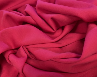 Puede incluir: Primer plano de una tela fluida de color magenta intenso. El material está drapeado, revelando pliegues y sombras que crean textura. El color uniforme sugiere una alta calidad, ideal para la confección de prendas.