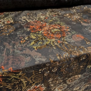 May include: Black sheer fabric with a floral pattern in shades of orange, brown, and green. The fabric has a textured, almost embossed look.