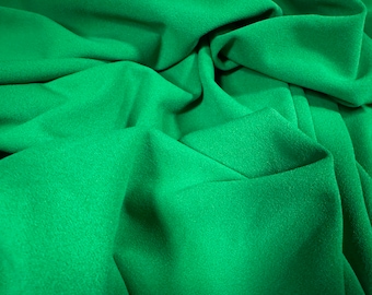 Puede incluir: Primer plano de una tela verde con superficie texturizada. La tela está doblada y drapeada, creando pliegues y arrugas suaves.