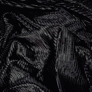 May include: Black fabric with a textured, ribbed pattern. The fabric is wrinkled and folded, creating a dramatic and abstract look.