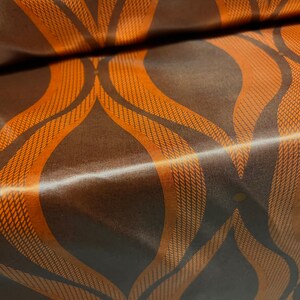 May include: Brown satin fabric with an orange patterned design of curved lines and dots.