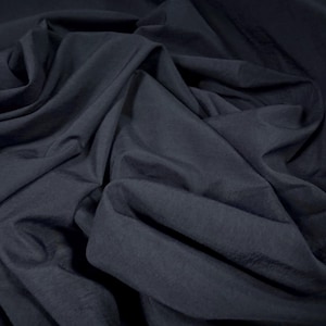May include: A close-up of a dark blue fabric with a smooth texture. The fabric is folded and draped, showing its soft and flowing nature.