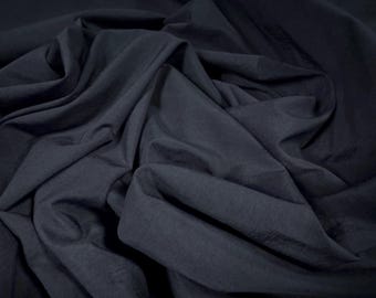 May include: A close-up of a dark blue fabric with a smooth texture. The fabric is folded and draped, showing its soft and flowing nature.