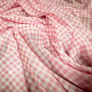 Könnte beinhalten: Rosa-weißes Gingham-Gewebe mit einer Netzstruktur. Der Stoff ist gefaltet und drapiert, wodurch Muster und Textur sichtbar werden.