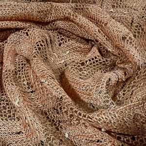 Puede incluir: Primer plano de una tela de crochet marrón con un delicado patrón de tejido abierto. La tela tiene un aspecto suave y texturizado y un acabado ligeramente brillante.