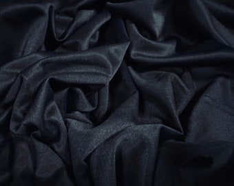May include: A close-up of a dark blue fabric with a smooth, silky texture. The fabric is draped and folded, creating a soft and luxurious look.