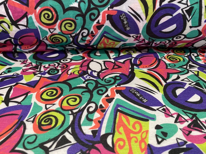 May include: White fabric with a colorful abstract print featuring swirls, geometric shapes, and the word "Holiness" repeated. The print is in shades of pink, green, blue, yellow, and black.