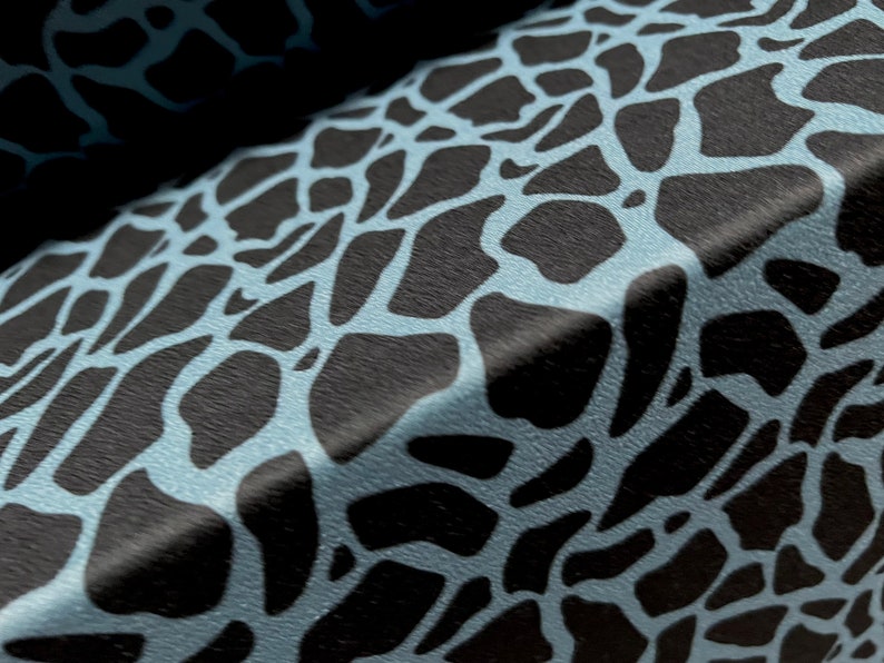 May include: Close-up of a blue and black fabric with a textured, irregular pattern resembling animal skin.