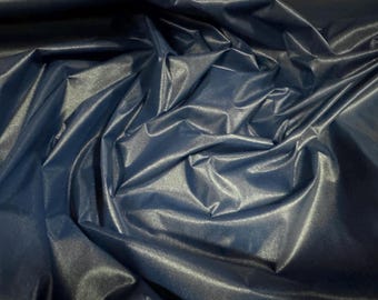 May include: A close-up of a smooth, dark blue fabric with a subtle sheen. The fabric is draped and folded, creating soft, flowing lines.
