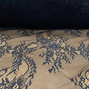 May include: Black lace fabric with a delicate floral pattern. The lace is sheer and has a soft, flowing texture.