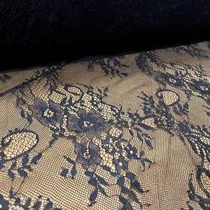 May include: Black lace fabric with a delicate floral pattern. The lace is sheer and has a soft, flowing texture.
