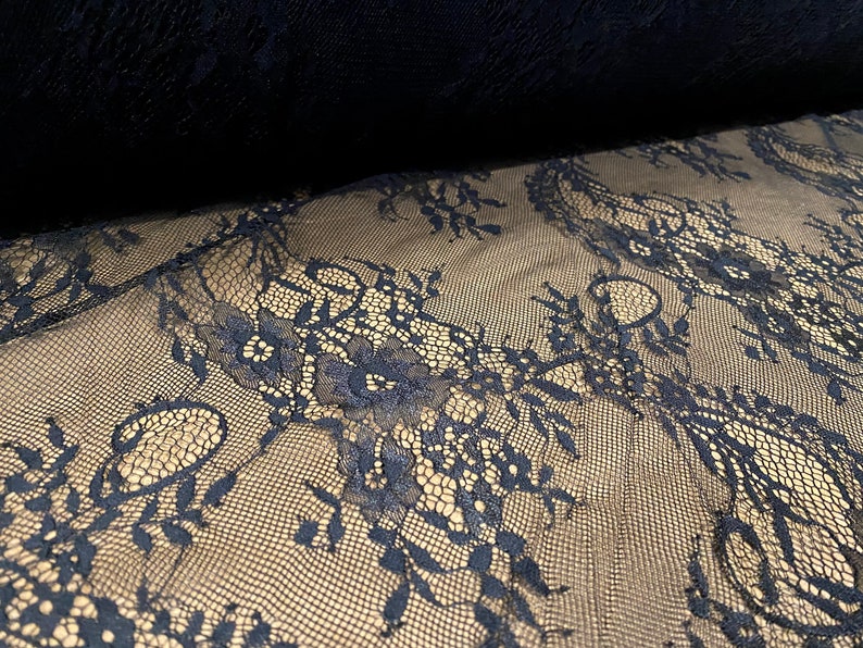 May include: Black lace fabric with a delicate floral pattern. The lace is sheer and has a soft, flowing texture.