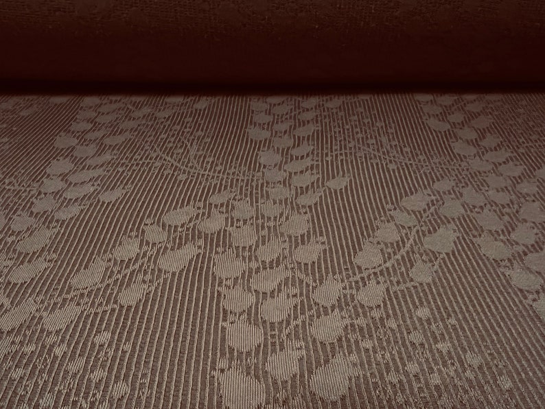 May include: Close-up of a brown fabric with a subtle embossed pattern of leaves and dots. The fabric has a textured, woven look.