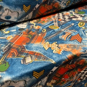 May include: Blue and orange fabric with a denim and plaid pattern. The fabric features various designs, including a zipper, a pin, a watch, and a bow.